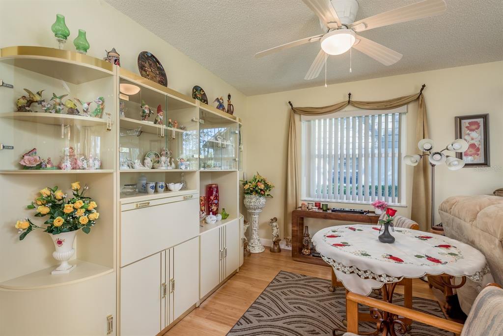 A dining room features a large display cabinet, a round table, and a ceiling fan — 3413 ROCHELLE COURT, CLEARWATER, FL