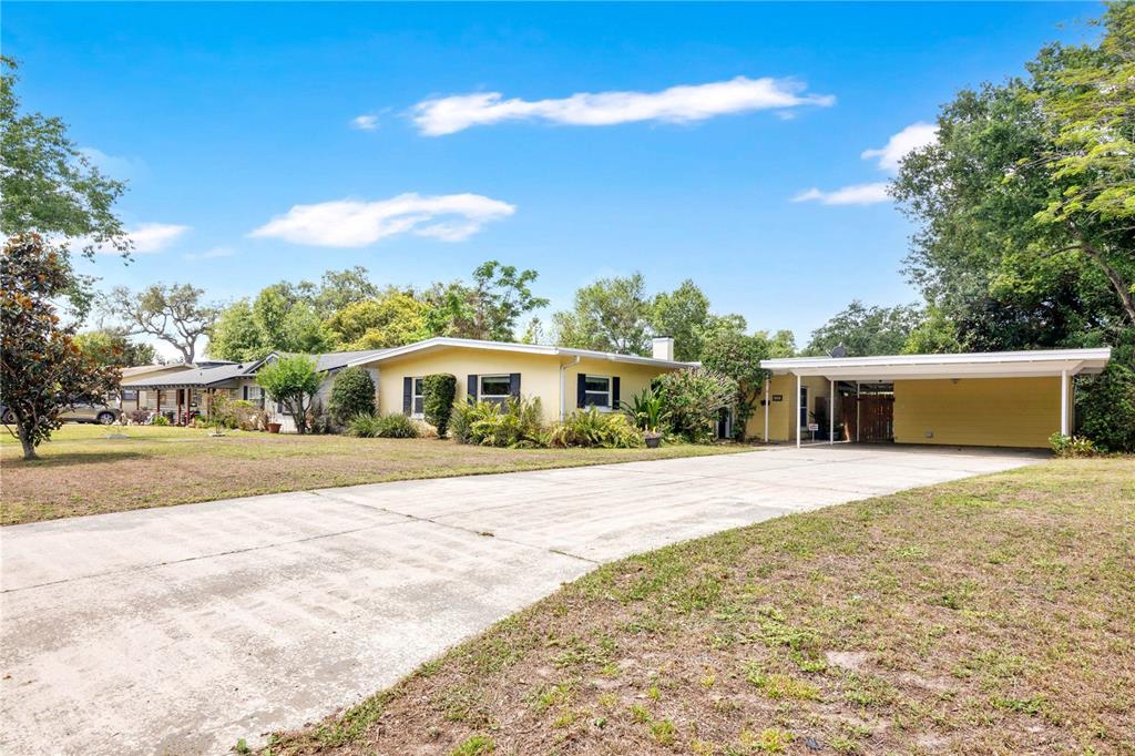 A yellow single-story house with a large concrete driveway and an attached carport — 5020 SAINT MARIE AVENUE, BELLE ISLE, FL
