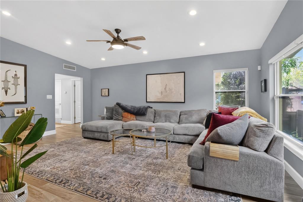 A living room features a large gray sectional sofa, a patterned rug, and a ceiling fan — 5020 SAINT MARIE AVENUE, BELLE ISLE, FL