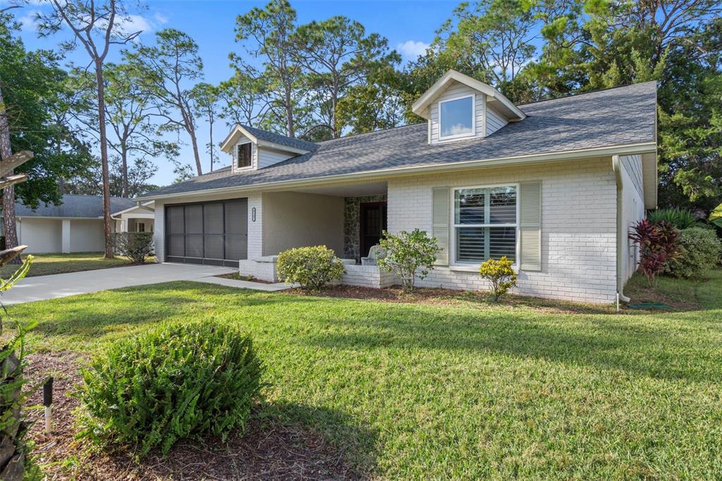A white brick house with a garage, two dormer windows, and a front lawn — 6147 TURNBURRY COURT, SPRING HILL, FL
