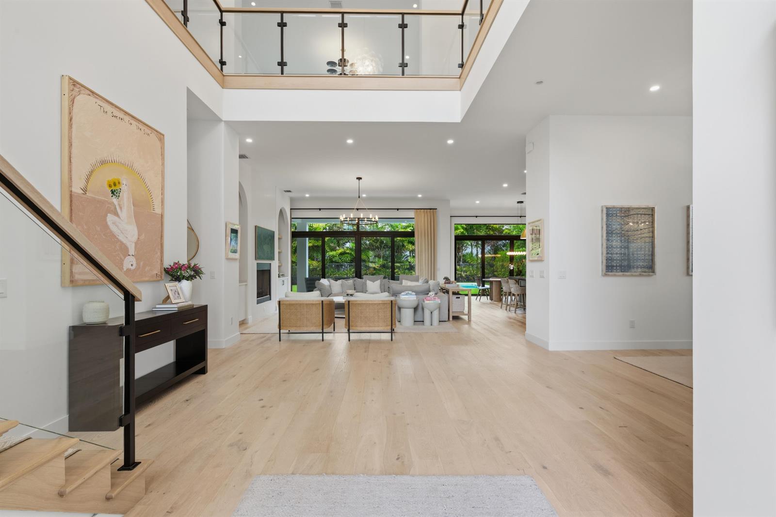 A bright, open-concept living area features light wood floors, a double-height ceiling, and glass railings — 9593 Vescovato Way, Boca Raton FL 33323, BOCA RATON, FL