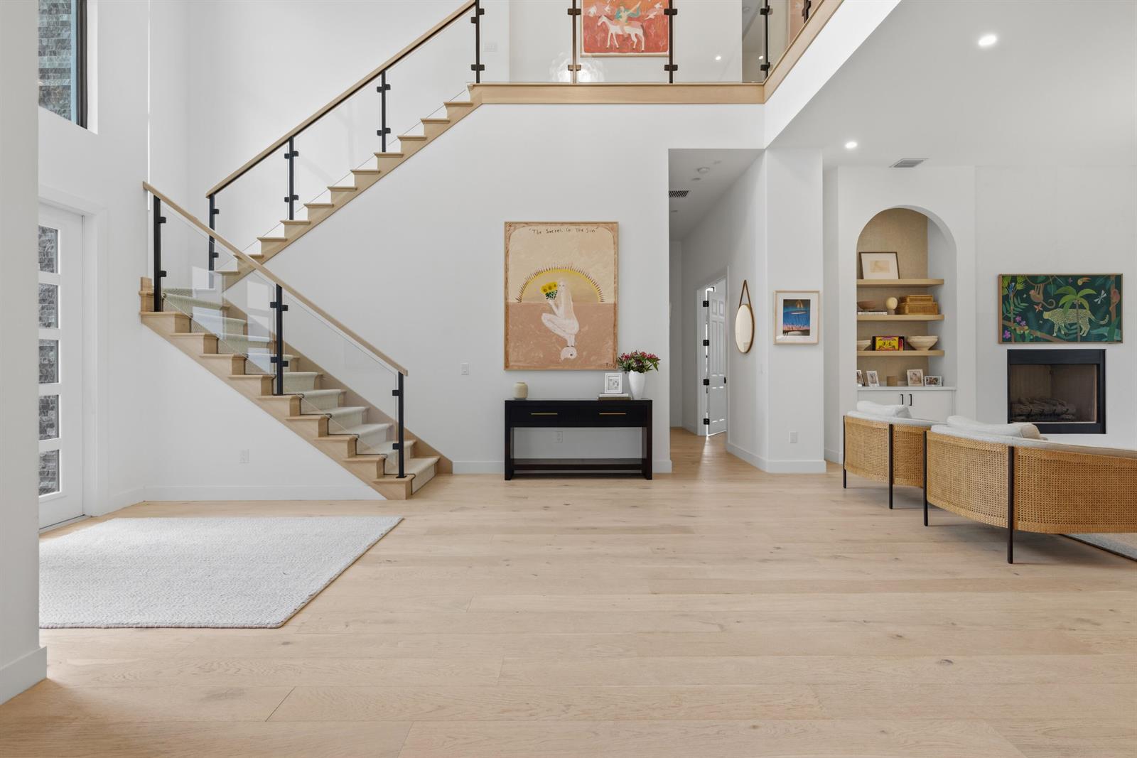 A bright, modern foyer features light wood floors, a glass-railed staircase, and a fireplace alcove — 9593 Vescovato Way, Boca Raton FL 33323, BOCA RATON, FL