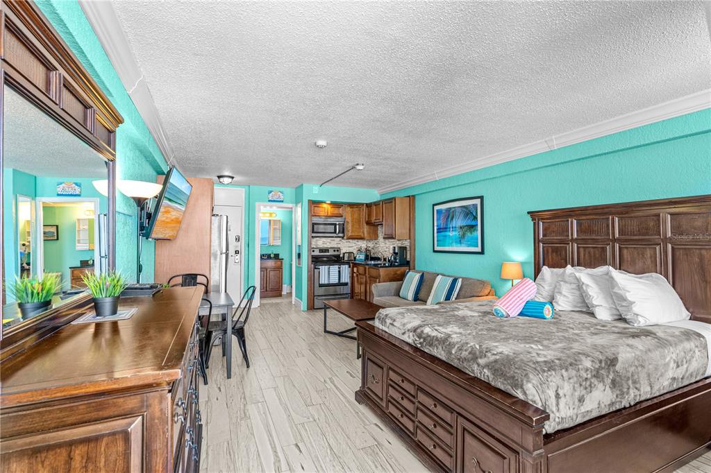 A studio hotel room features a bed, kitchenette, dining area, and bright turquoise walls — 2301 S ATLANTIC AVENUE UNIT 339, DAYTONA BEACH, FL
