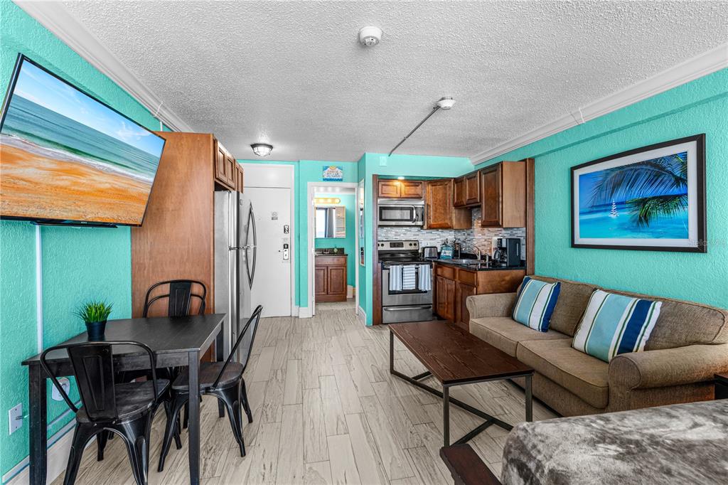 A studio apartment features a kitchenette, dining area, sofa, and turquoise walls with tile flooring — 2301 S ATLANTIC AVENUE UNIT 339, DAYTONA BEACH, FL