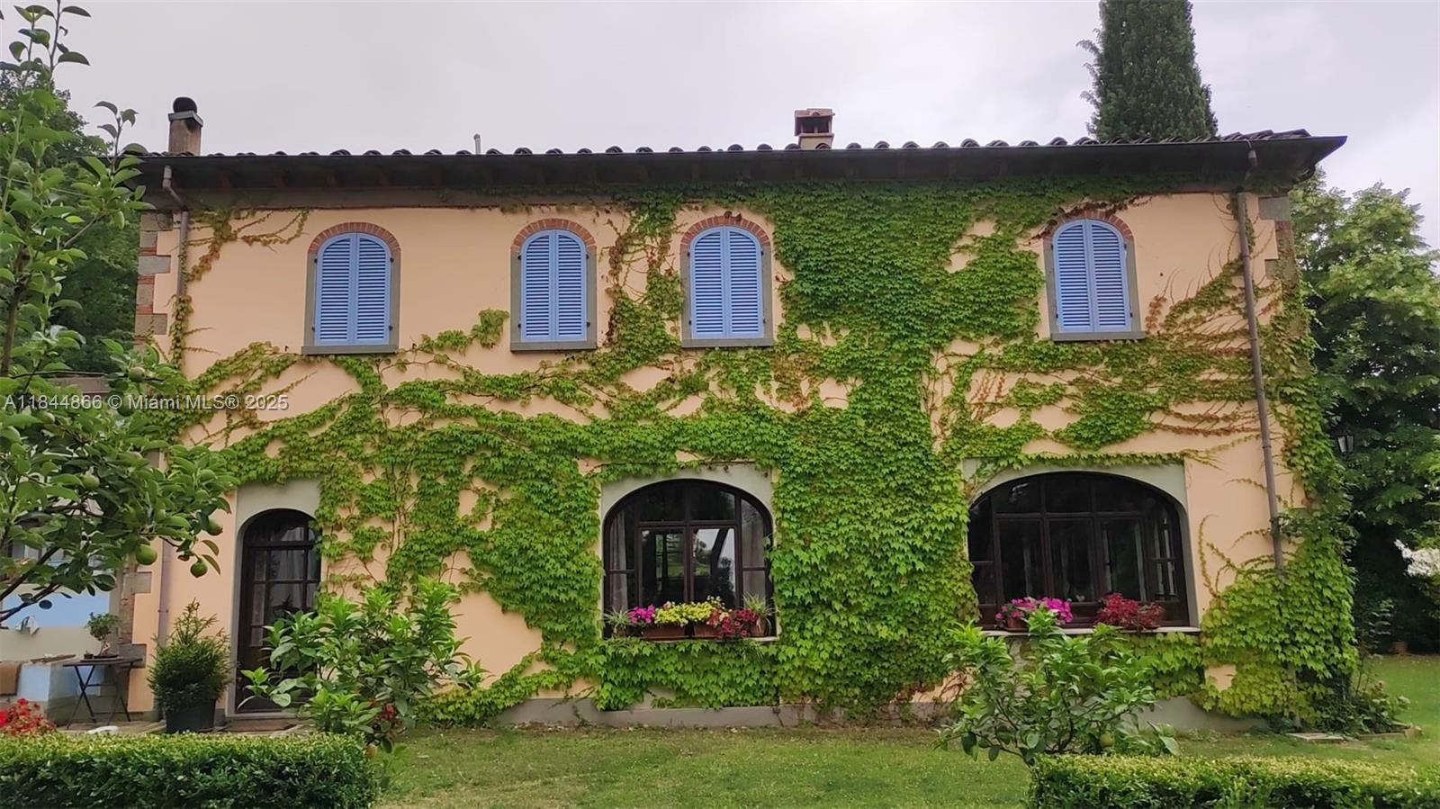 A two-story stucco house with blue shutters and ivy covering the exterior walls — 74 Castelnuovo - Subbiano, Tuscany, IA 52010, IA