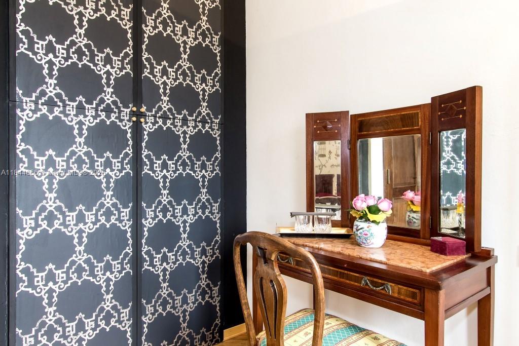 A vanity with a tri-fold mirror sits beside a closet featuring dark patterned doors — 74 Castelnuovo - Subbiano, Tuscany, IA 52010, IA