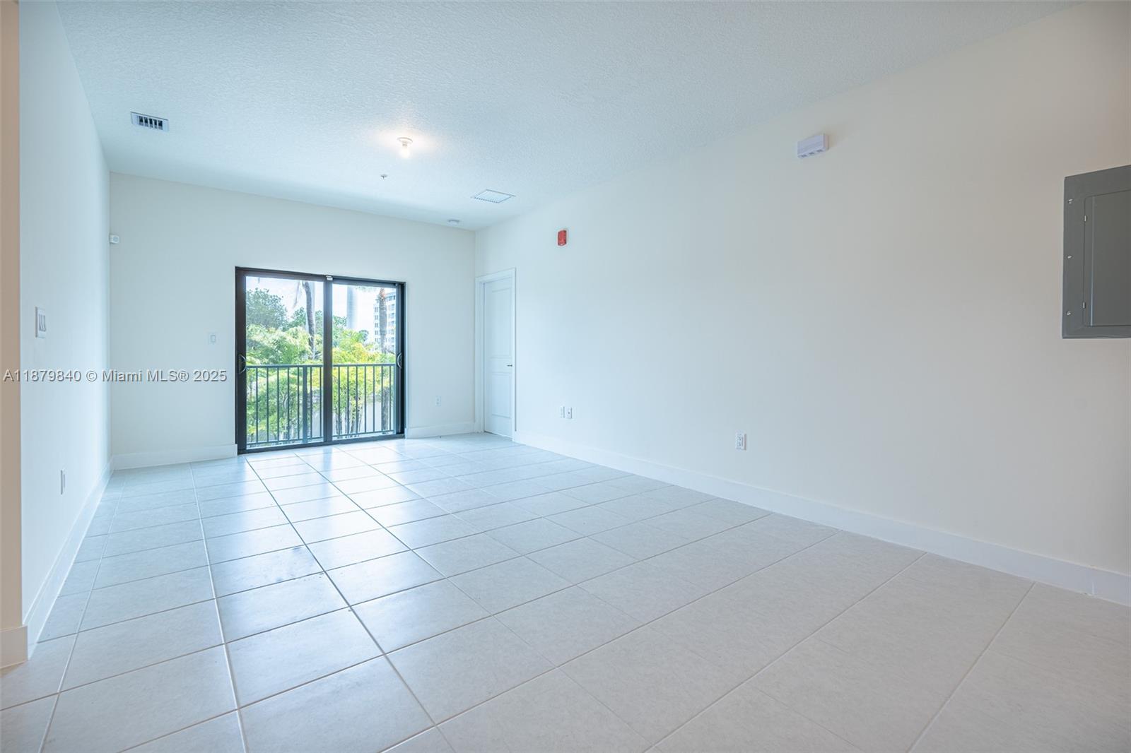 An empty room features white walls, light-colored tile flooring, and a sliding glass balcony door — 8001 NW 41st St # 208, Doral FL 33166, DORAL, FL