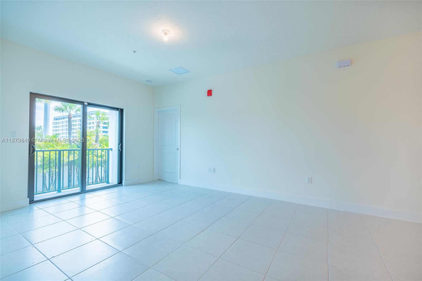 An empty room features light-colored tile flooring, white walls, and a sliding glass balcony door — 8001 NW 41st St # 208, Doral FL 33166, DORAL, FL