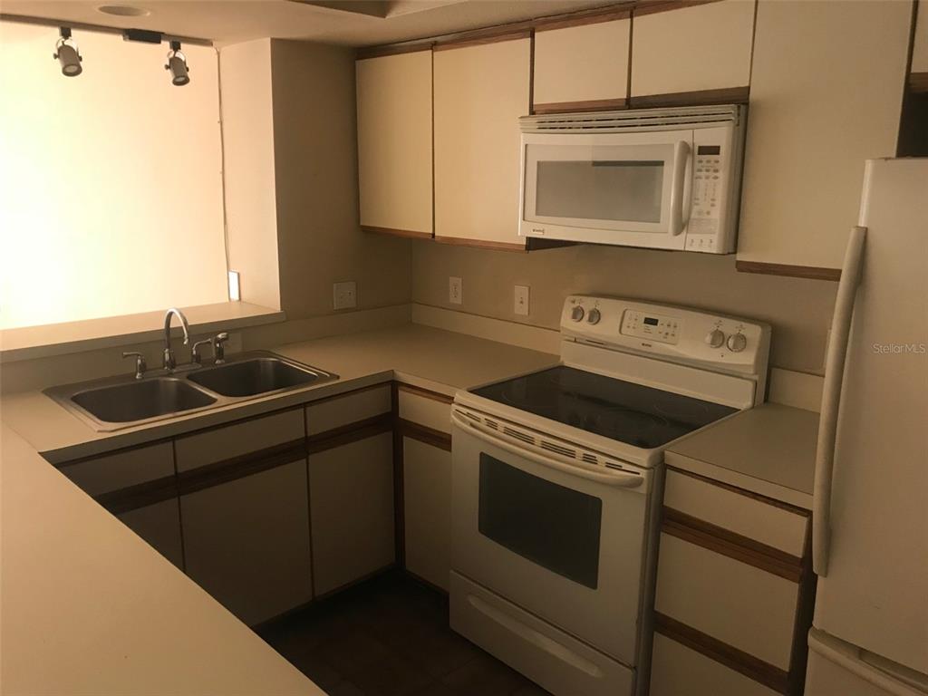 A kitchen features white cabinets, white appliances, a double sink, and beige countertops — 2599 DOLLY BAY DRIVE UNIT 204, PALM HARBOR, FL