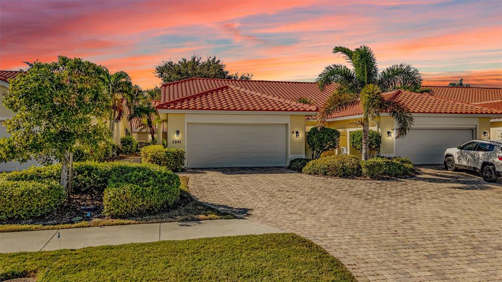 A single-story house with a two-car garage and a paved driveway at sunset — 3841 ALBACETE CIRCLE UNIT 51, PUNTA GORDA, FL
