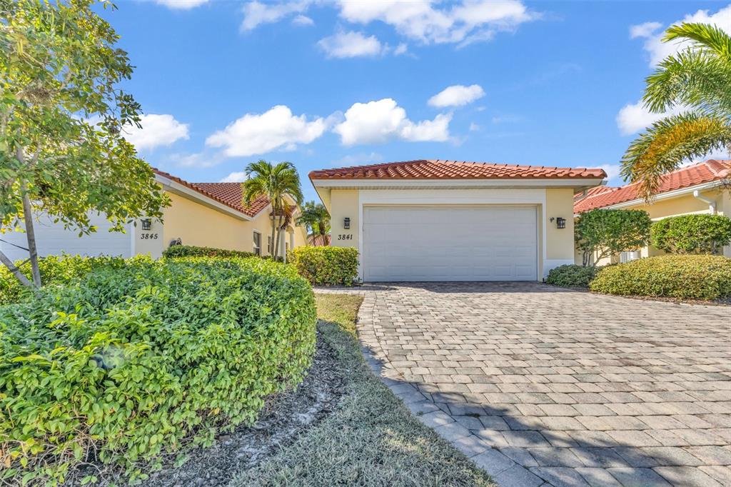Two adjacent single-story houses with tiled roofs and paved driveways under a blue sky — 3841 ALBACETE CIRCLE UNIT 51, PUNTA GORDA, FL