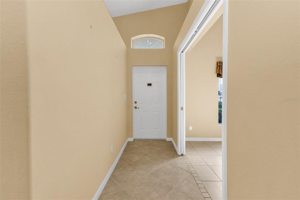 An entryway features tan walls, tile flooring, a white front door, and a transom window — 3841 ALBACETE CIRCLE UNIT 51, PUNTA GORDA, FL