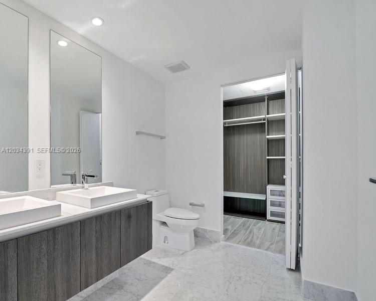 A modern bathroom features a double vanity, a toilet, and an open walk-in closet — 801 S Miami Ave # 1807, Miami FL 33130, MIAMI, FL