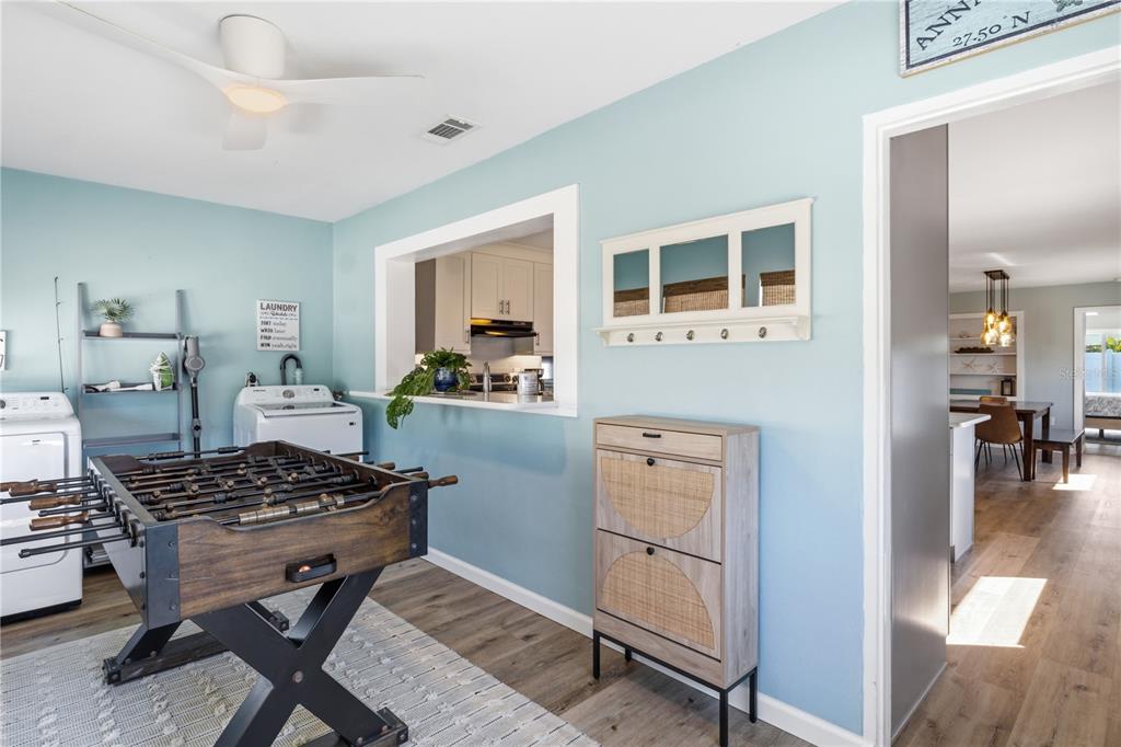 A laundry room features a foosball table, light blue walls, and a pass-through to the kitchen — 205 HAVERKOS COURT, HOLMES BEACH, FL