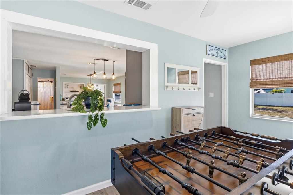A foosball table sits in a light blue room with a kitchen pass-through window — 205 HAVERKOS COURT, HOLMES BEACH, FL