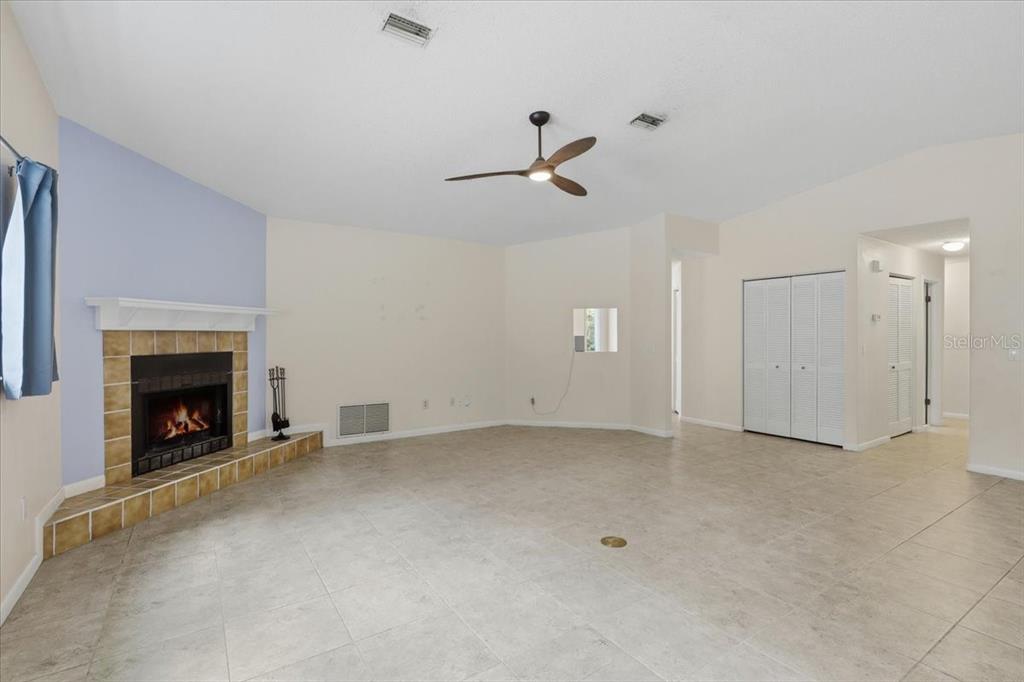 A living room features tile flooring, a fireplace with a tiled hearth, and a ceiling fan — 15 WASSERMAN DRIVE, PALM COAST, FL