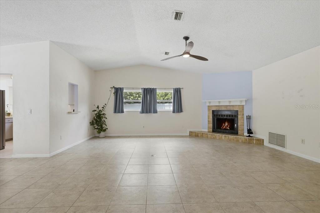 A living room features tile flooring, a vaulted ceiling, a ceiling fan, and a fireplace — 15 WASSERMAN DRIVE, PALM COAST, FL