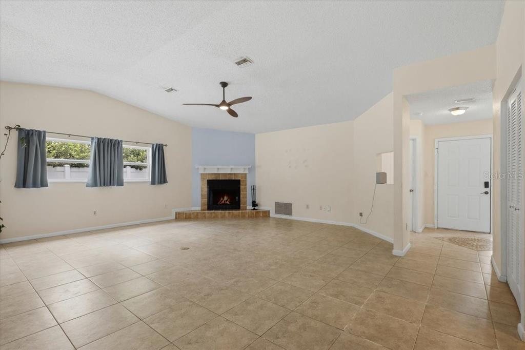 A spacious living room features tile flooring, a corner fireplace, and a white front door — 15 WASSERMAN DRIVE, PALM COAST, FL