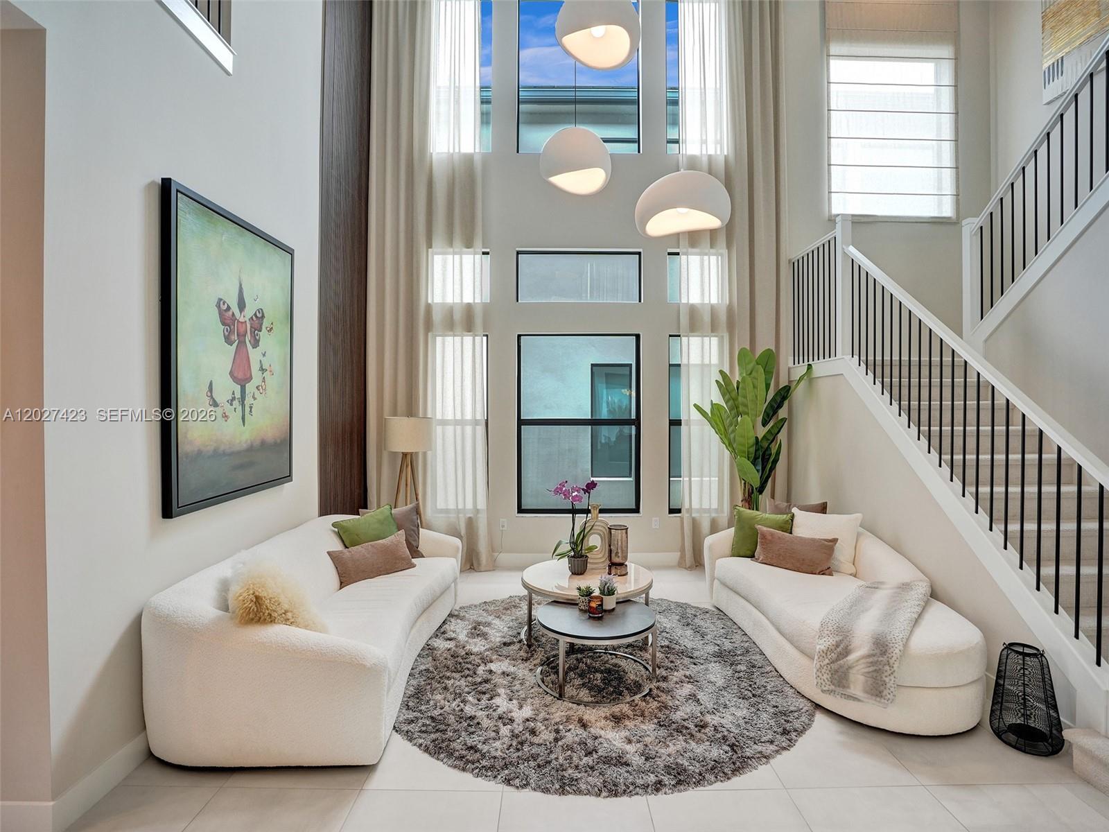 A high-ceilinged living room features two white curved sofas, a round rug, and large windows — 8642 Swinley Forest Way, Boca Raton FL 33434, BOCA RATON, FL