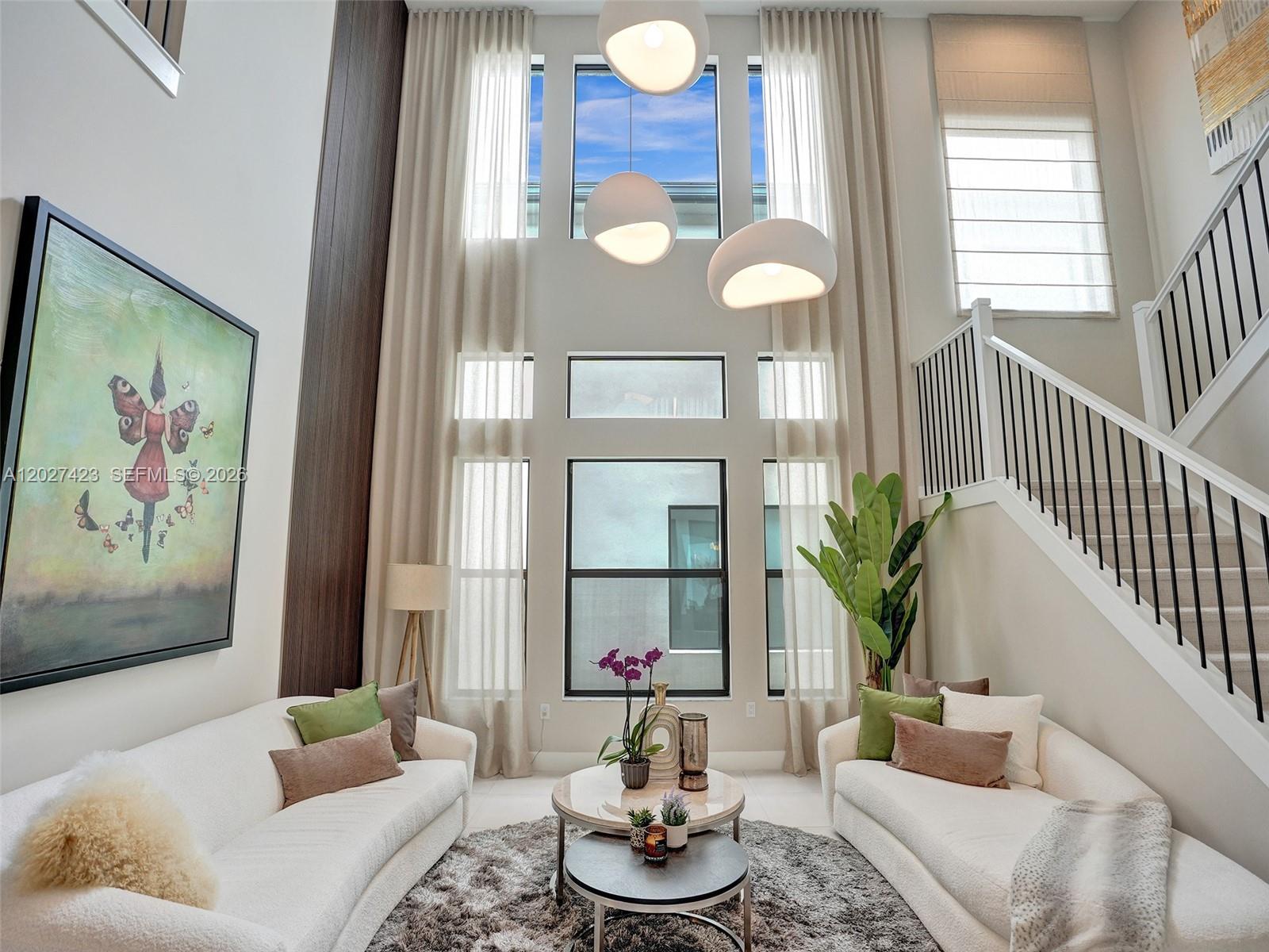 A bright living room features high ceilings, floor-to-ceiling windows, two white sofas, and a staircase — 8642 Swinley Forest Way, Boca Raton FL 33434, BOCA RATON, FL