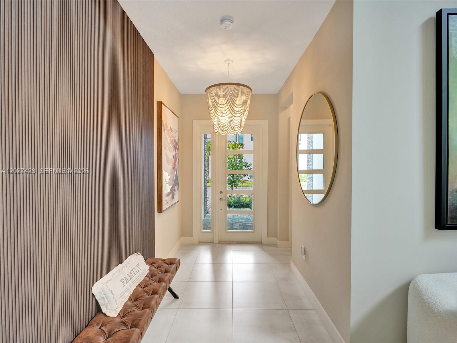 A bright entryway features a slatted wood wall, a tufted bench, and a beaded chandelier — 8642 Swinley Forest Way, Boca Raton FL 33434, BOCA RATON, FL