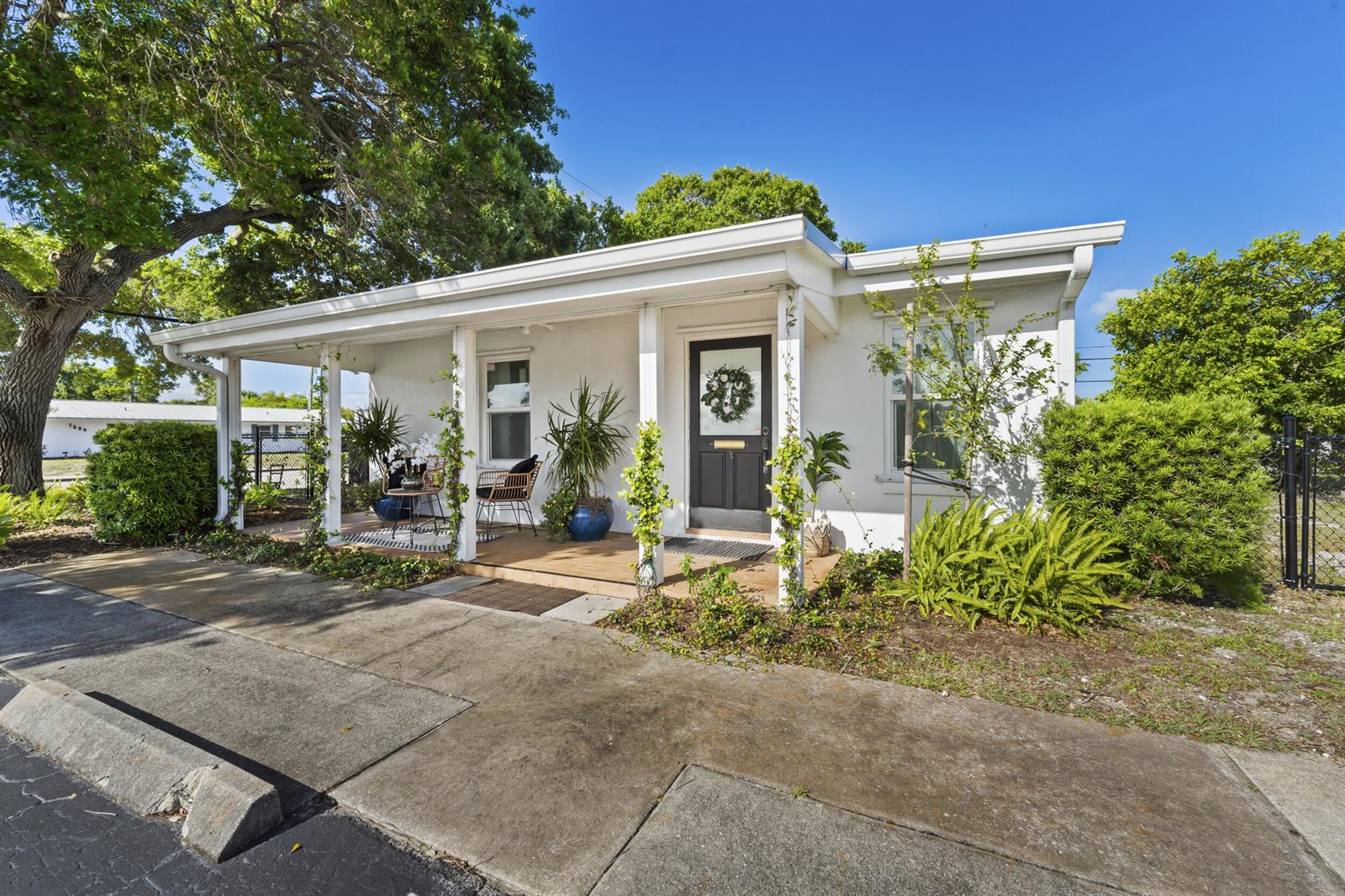 A white single-story house features a covered front porch with a dark door and landscaping — 1324 16th Street, Vero Beach FL 32960, VERO BEACH, FL
