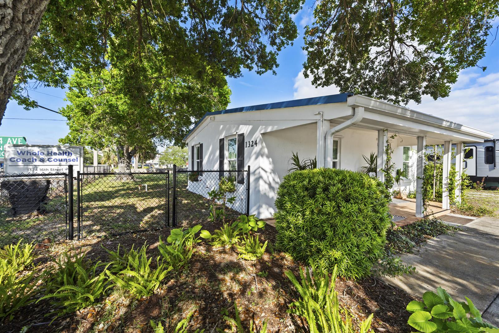 A white single-story building with a covered porch and a chain-link fence in front — 1324 16th Street, Vero Beach FL 32960, VERO BEACH, FL