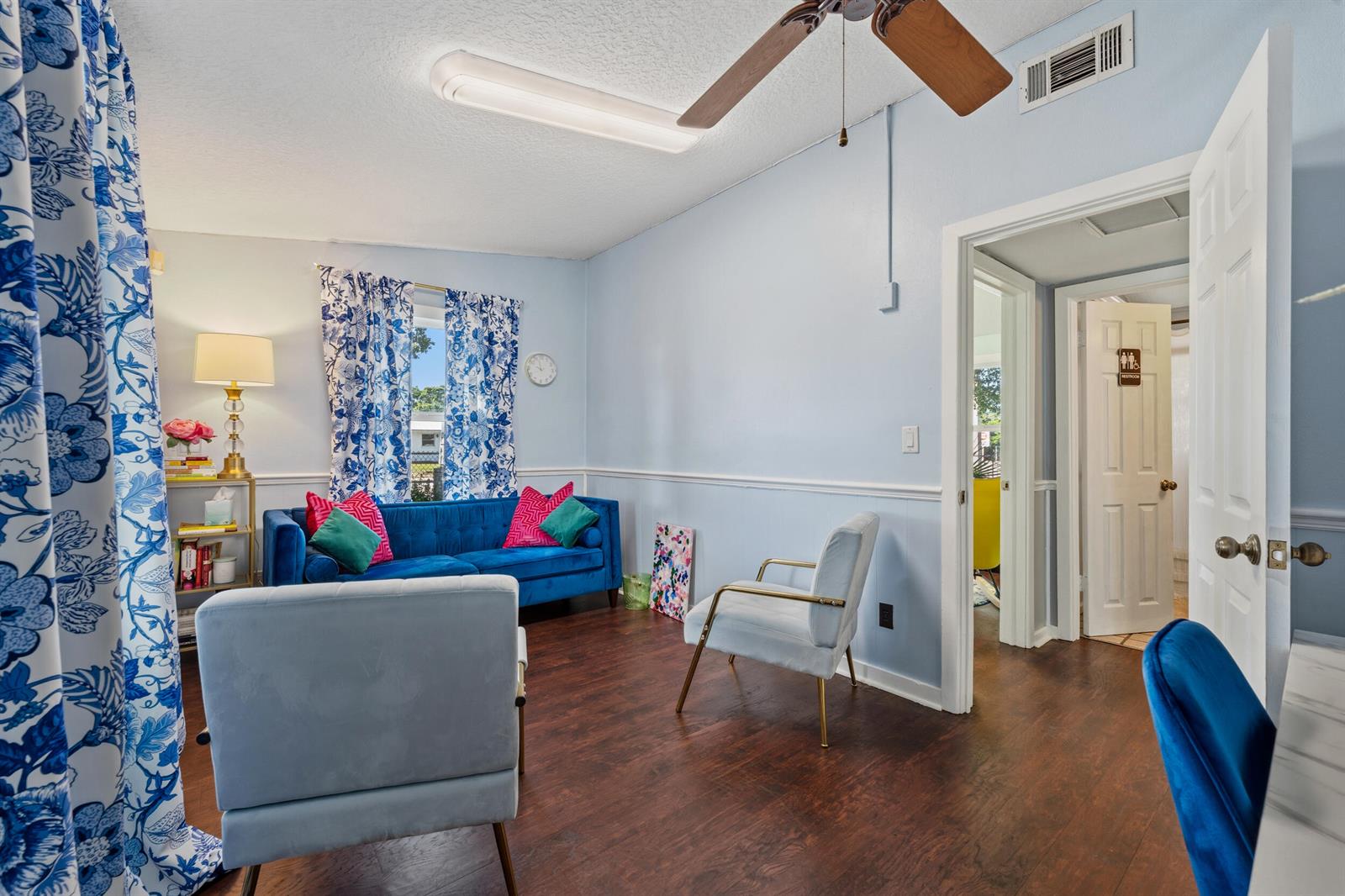 A living room with blue walls, a blue velvet sofa, and two light-colored armchairs — 1324 16th Street, Vero Beach FL 32960, VERO BEACH, FL
