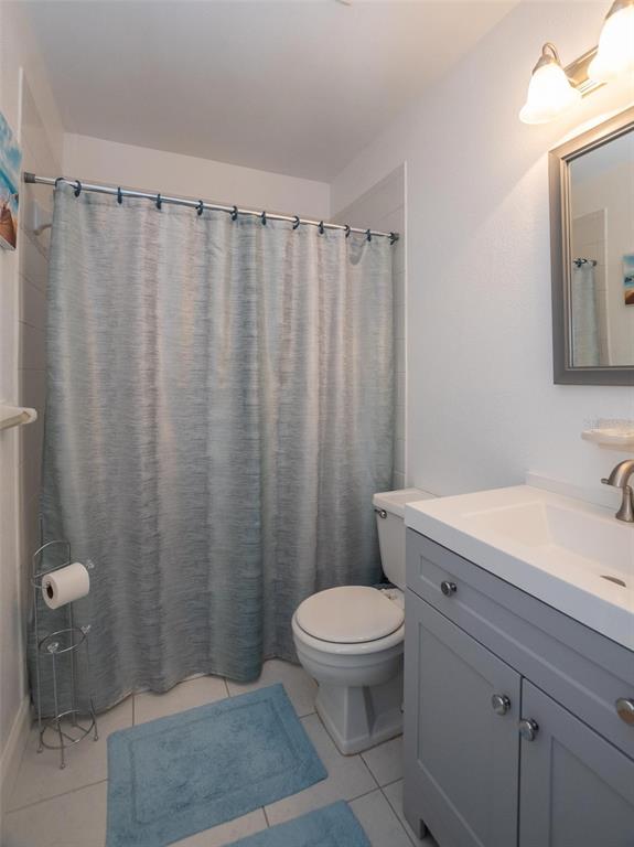 A bathroom features a gray vanity, a white toilet, and a blue shower curtain — 4849 SAXON DRIVE UNIT C202, NEW SMYRNA BEACH, FL