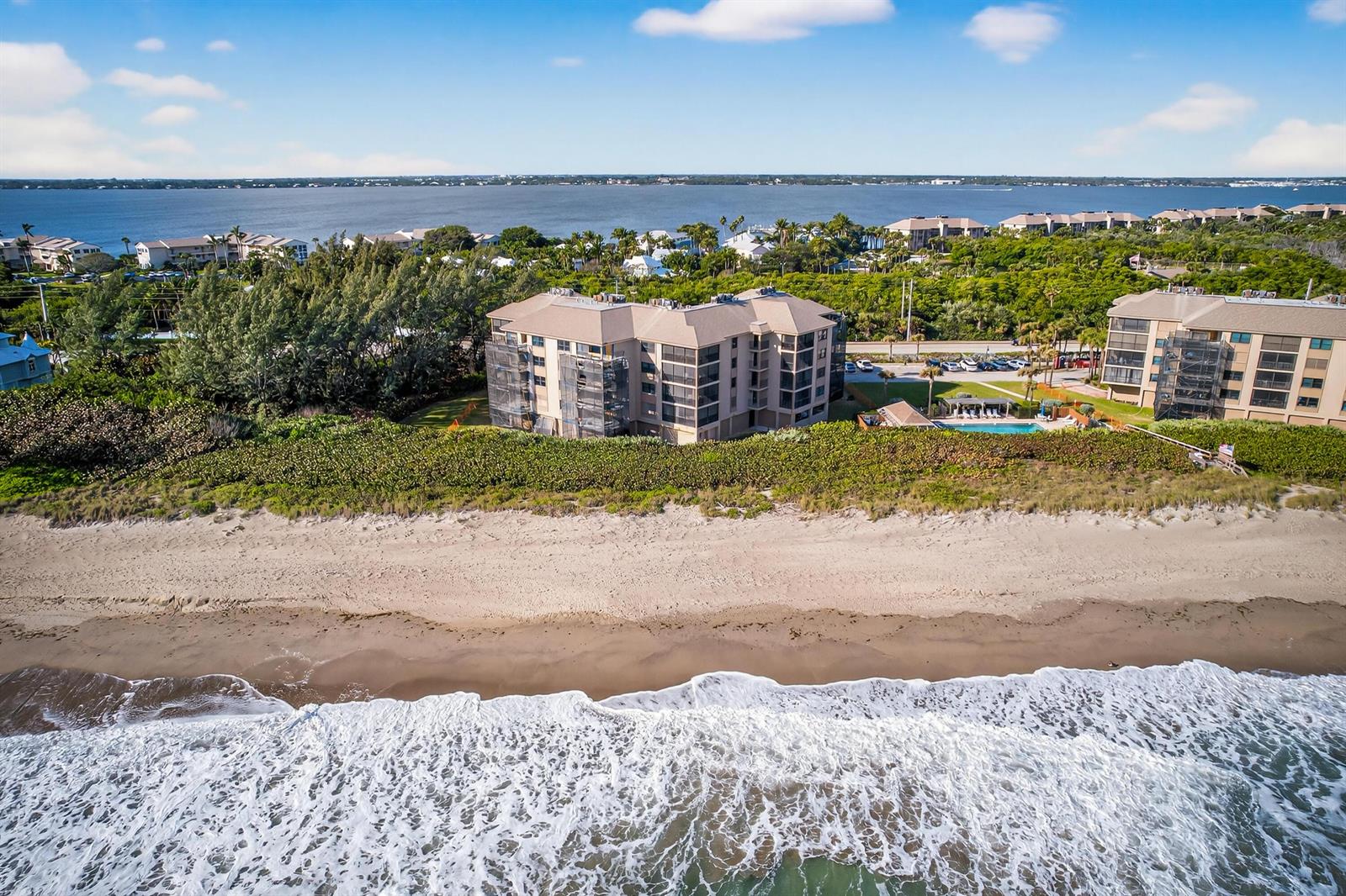 An aerial view shows a multi-story beachfront condominium building with a pool and parking — 2491 NE Ocean Boulevard # 106, Stuart FL 34996, STUART, FL