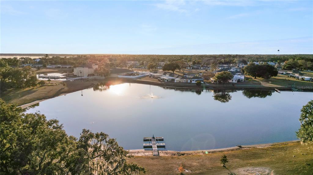 An aerial view shows a lake with a wooden dock and a fountain in a neighborhood — 4311 CLUB CIRCLE, LAKESHORE, FL