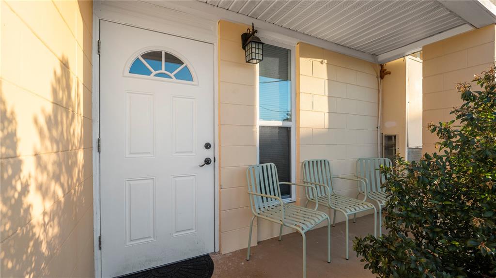 A white front door and three metal chairs sit on a covered concrete porch — 4311 CLUB CIRCLE, LAKESHORE, FL