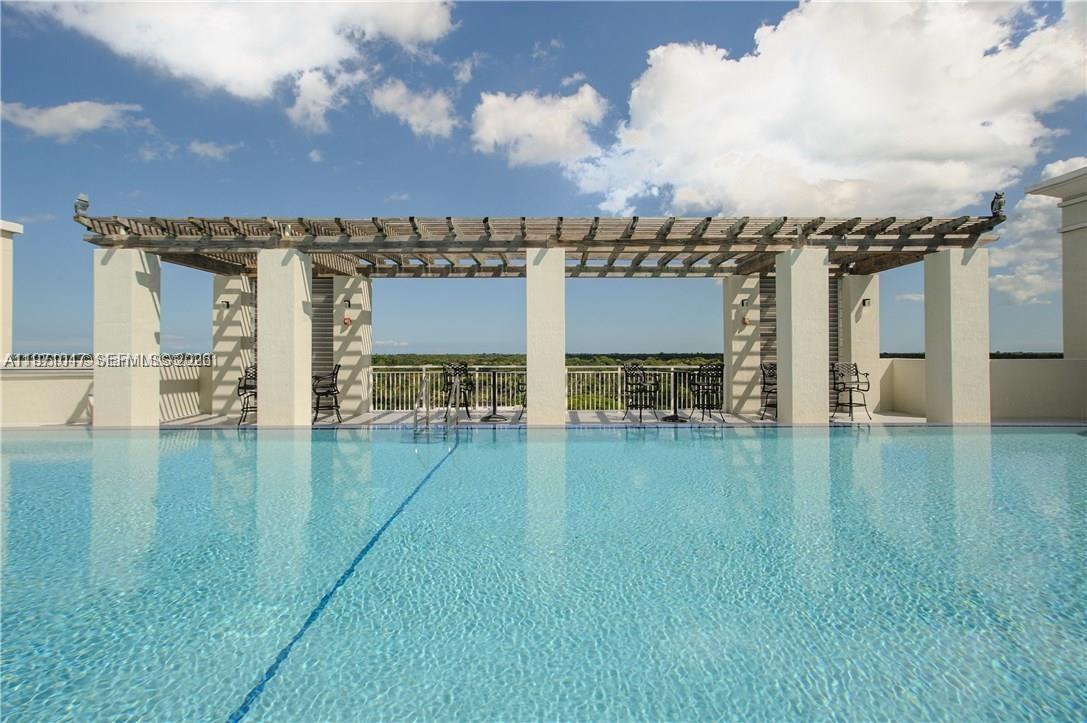 A rooftop swimming pool features a wooden pergola supported by white pillars overlooking a landscape — 7275 SW 90th St # C312, Miami FL 33156, MIAMI, FL