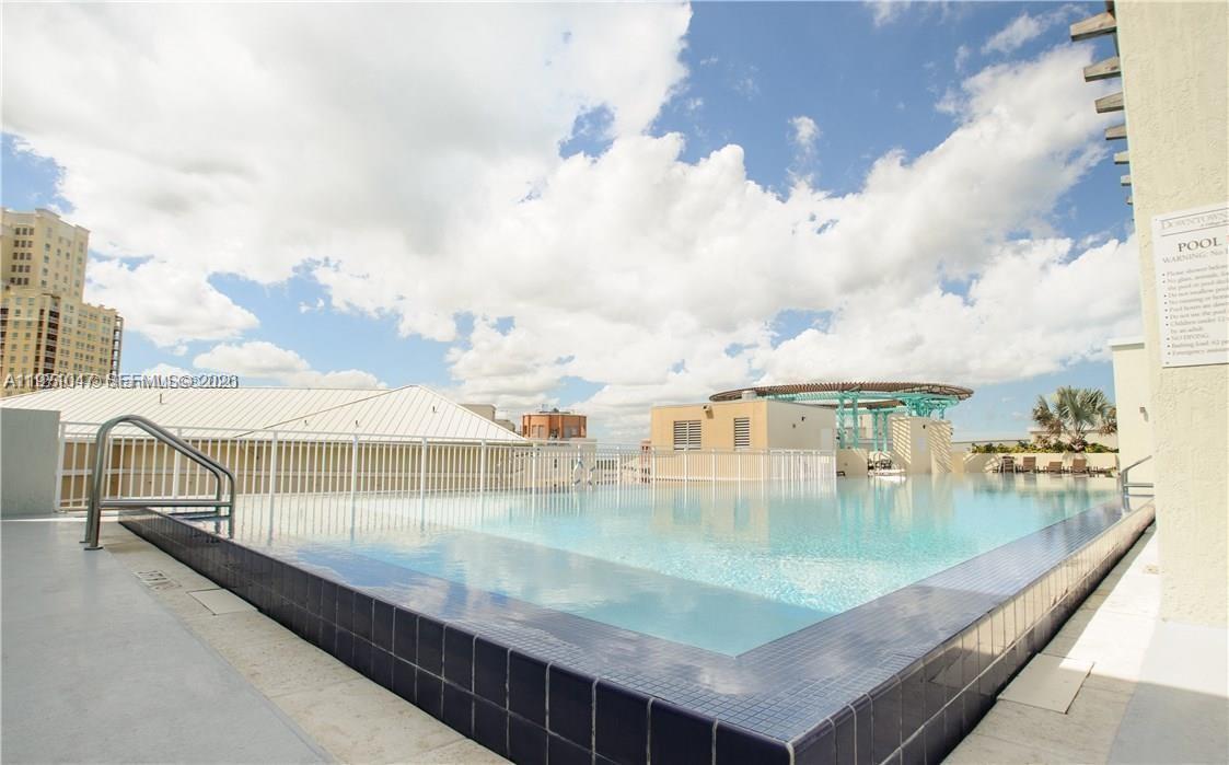A rooftop swimming pool with a white fence and a view of surrounding buildings — 7275 SW 90th St # C312, Miami FL 33156, MIAMI, FL