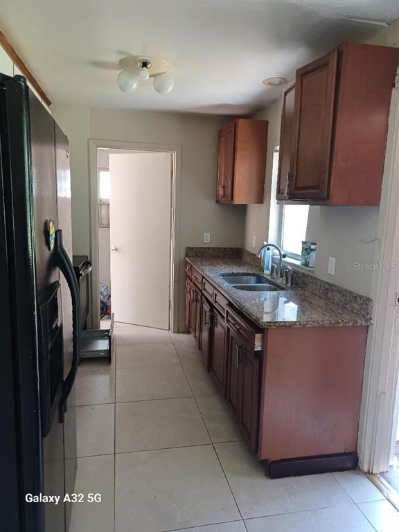 A galley kitchen features wood cabinets, granite countertops, and light-colored tile flooring — 6408 SUNSHINE STREET, ORLANDO, FL