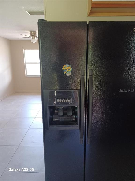 A black side-by-side refrigerator stands in a kitchen with tiled floors — 6408 SUNSHINE STREET, ORLANDO, FL