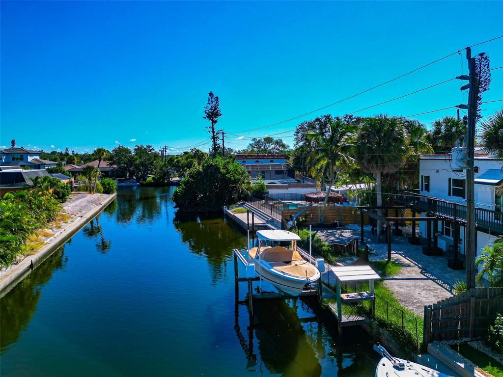 A boat sits on a lift in a canal next to a residential backyard — 681 AVENIDA DE MAYO, SARASOTA, FL