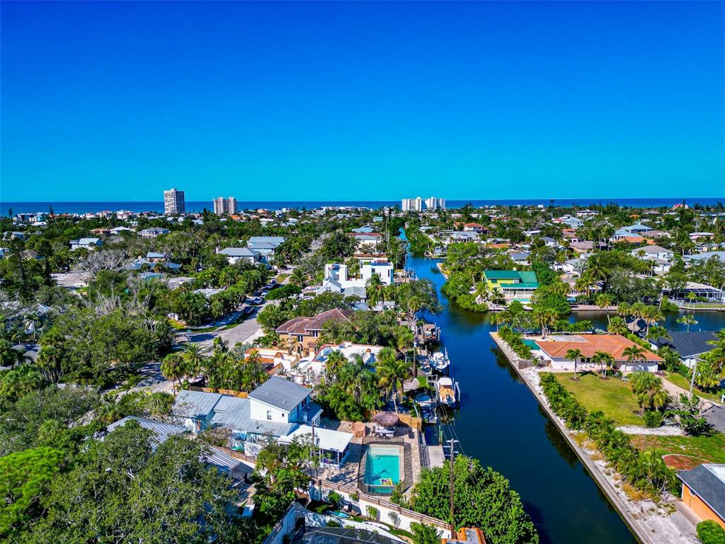 An aerial view of a coastal neighborhood featuring houses, a canal, and the ocean beyond — 681 AVENIDA DE MAYO, SARASOTA, FL