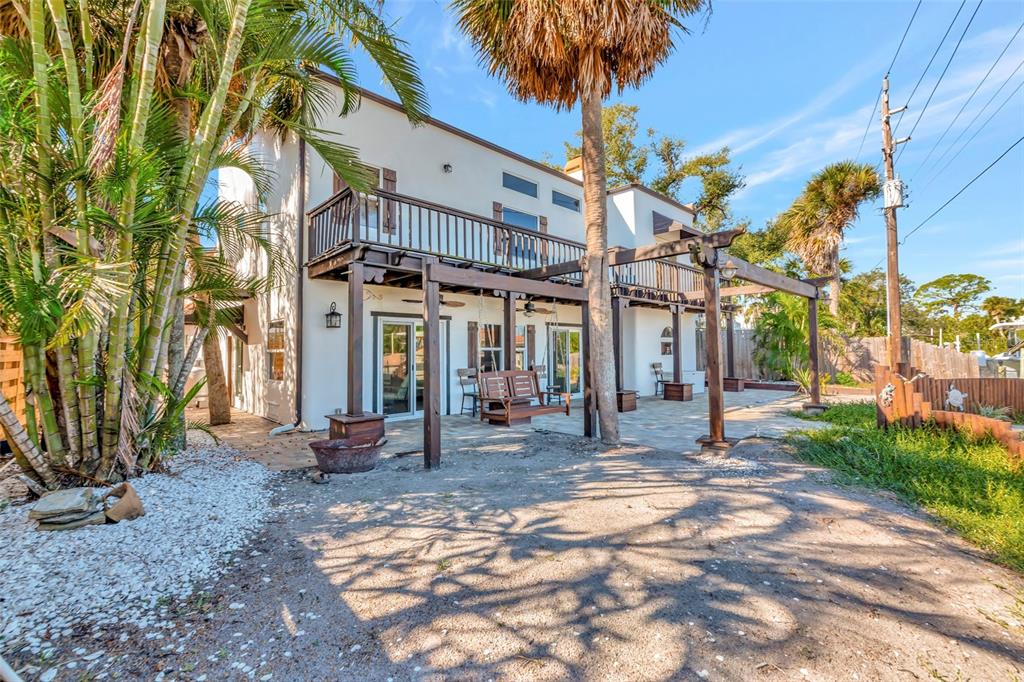 A two-story white stucco house features a wooden pergola, a balcony, and a patio area — 681 AVENIDA DE MAYO, SARASOTA, FL