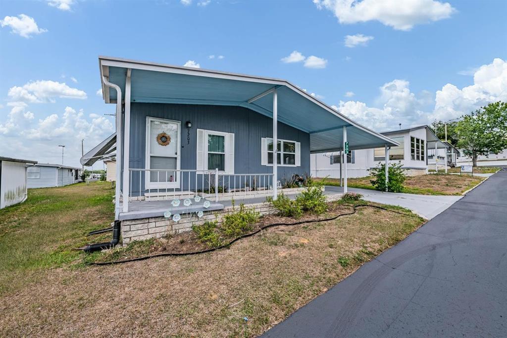 A blue mobile home with a covered carport and a small front porch — 7203 EL MEYERS STREET, ZEPHYRHILLS, FL