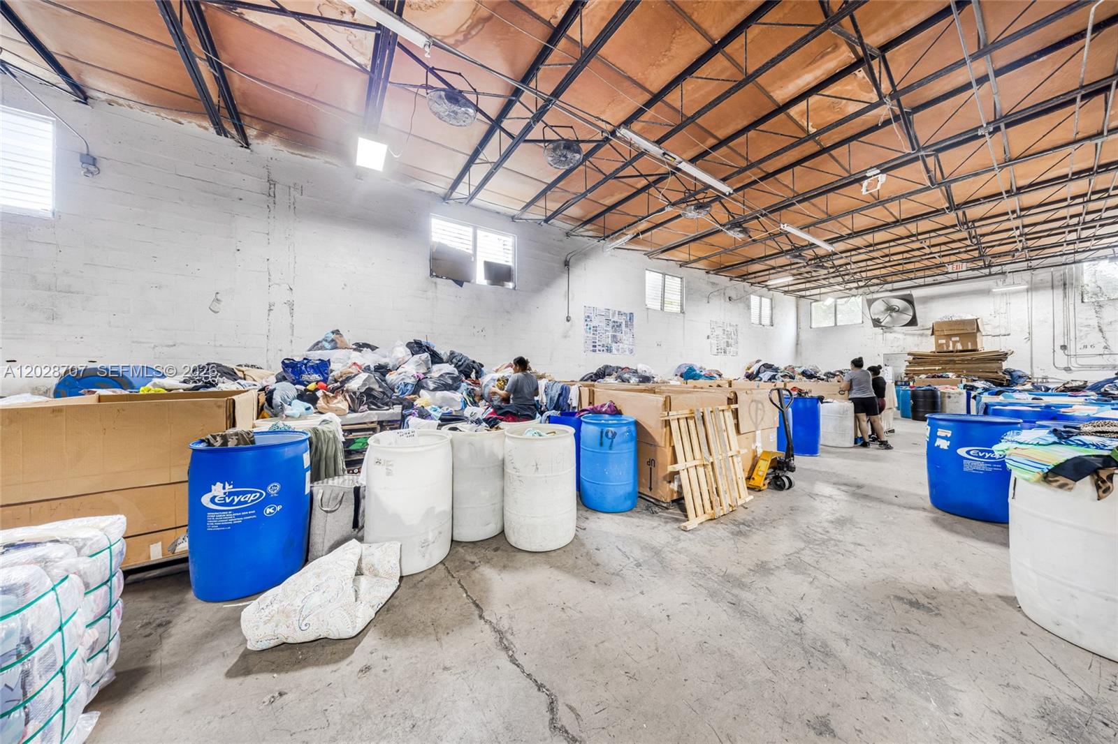 This warehouse space features exposed ceilings, concrete floors, and numerous large plastic storage bins — 1085 E 27th St, Hialeah FL 33013, HIALEAH, FL