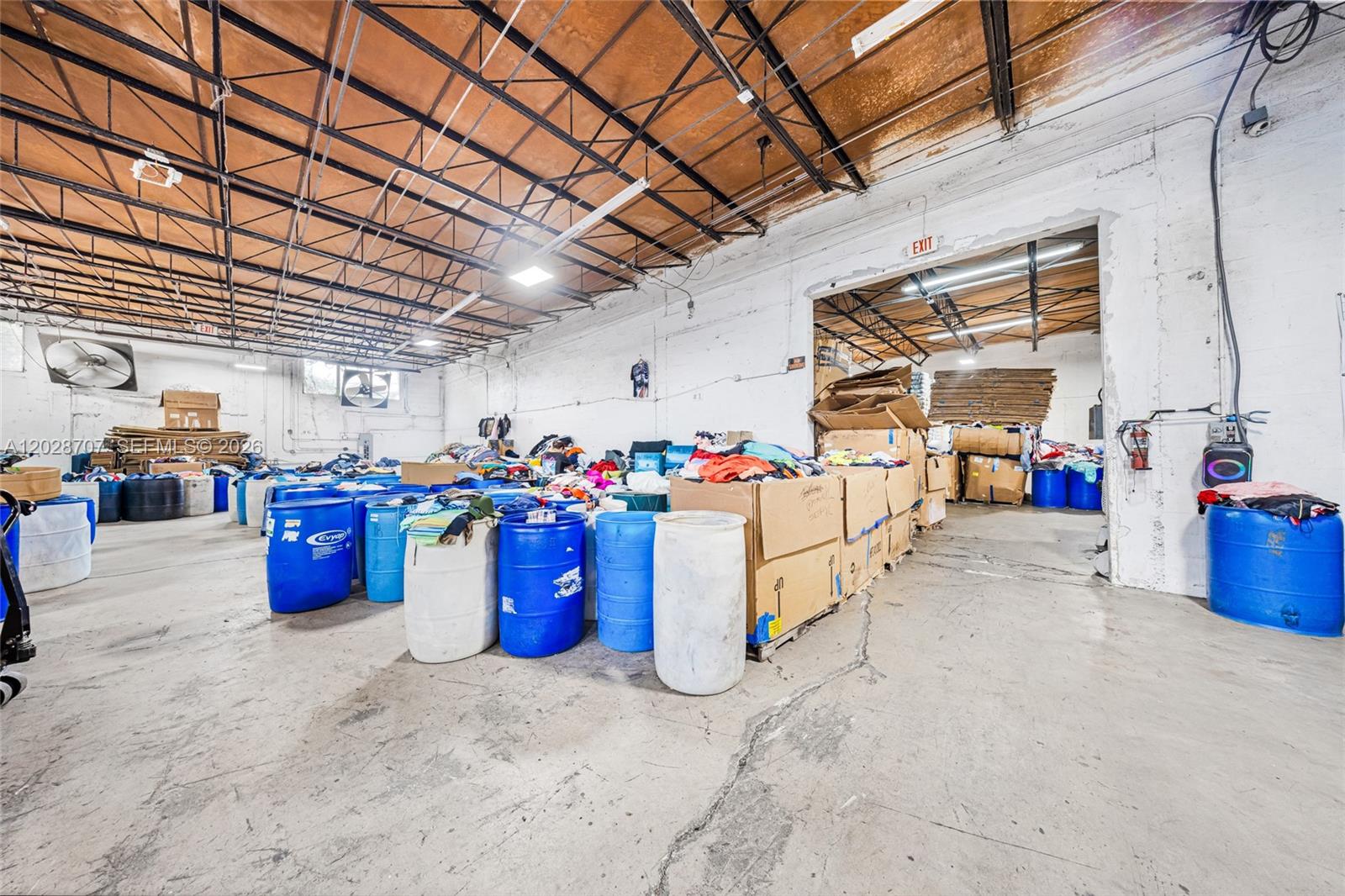 A large industrial warehouse space features concrete floors, exposed ceiling trusses, and numerous storage barrels — 1085 E 27th St, Hialeah FL 33013, HIALEAH, FL