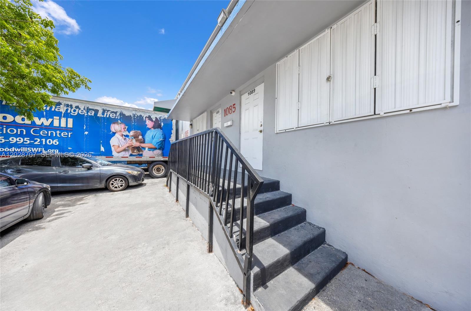 An exterior view shows a grey building with a black metal railing and concrete stairs — 1085 E 27th St, Hialeah FL 33013, HIALEAH, FL