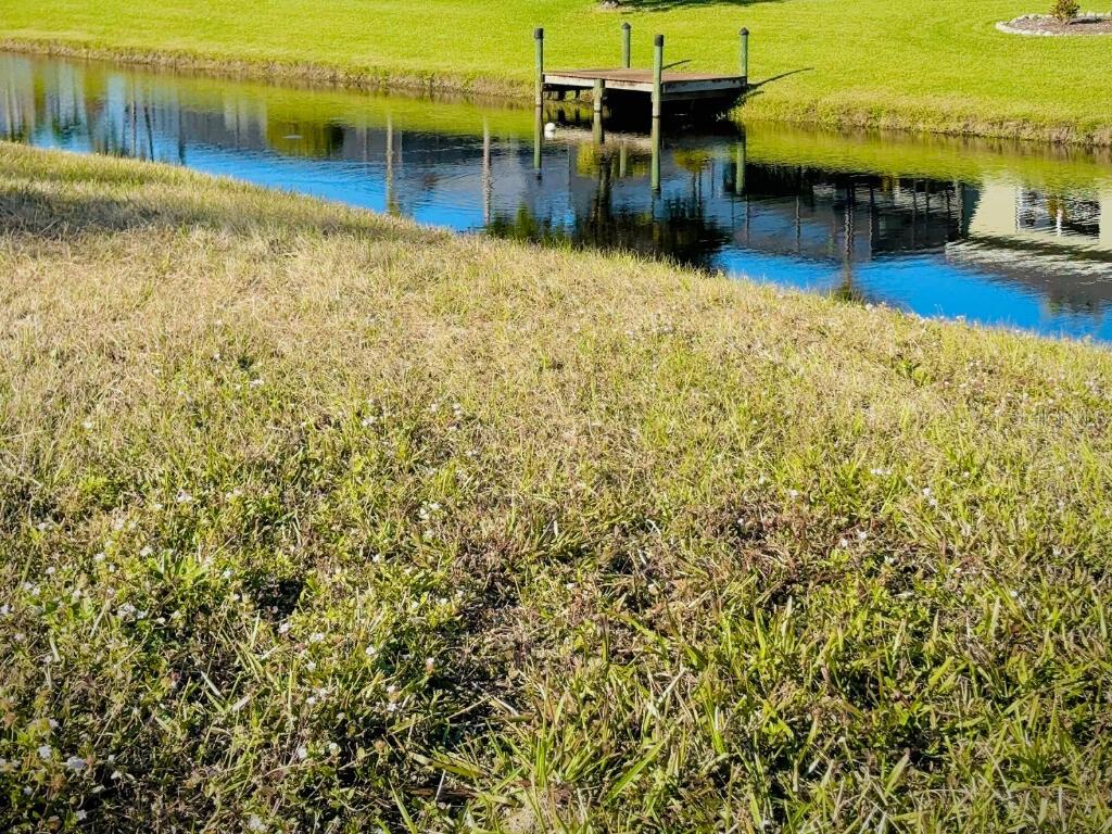 A small wooden dock extends into a narrow canal bordered by grassy lawns — 683 ROTONDA CIRCLE, ROTONDA WEST, FL