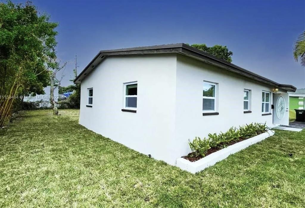 A white, single-story house exterior features a grassy yard and several windows — 710 SW 9TH STREET, DELRAY BEACH, FL