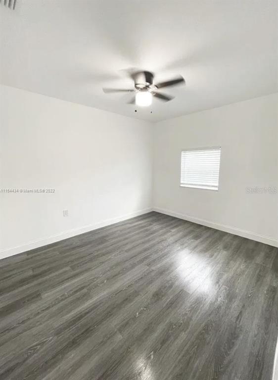 An empty bedroom features white walls, a ceiling fan, and gray wood-look flooring — 710 SW 9TH STREET, DELRAY BEACH, FL