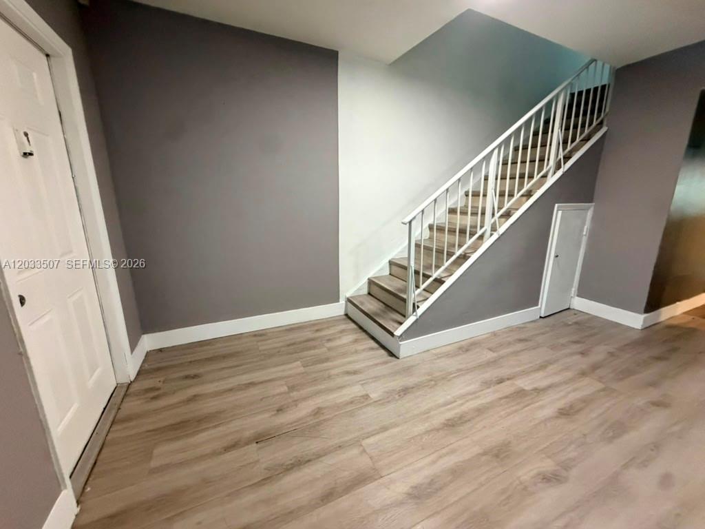 A room features light wood-look flooring, gray walls, and a staircase with white railings — 274 NE 141st St # 3C, Miami FL 33161, MIAMI, FL