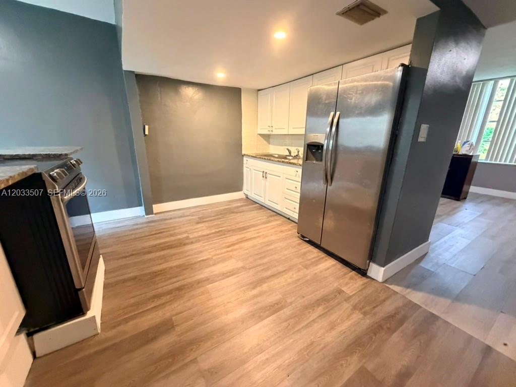 A kitchen features stainless steel appliances, white cabinetry, and light wood-look flooring — 274 NE 141st St # 3C, Miami FL 33161, MIAMI, FL