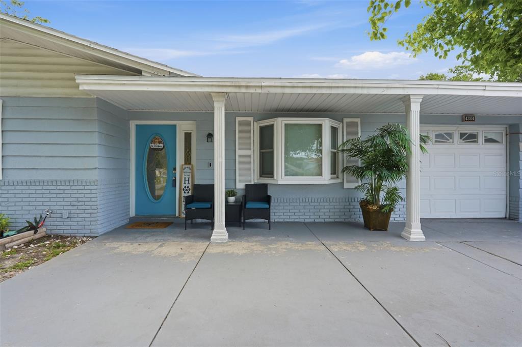The exterior of a light blue house features a front porch, garage, and blue door — 4344 OAK BLUFF AVENUE, HOLIDAY, FL