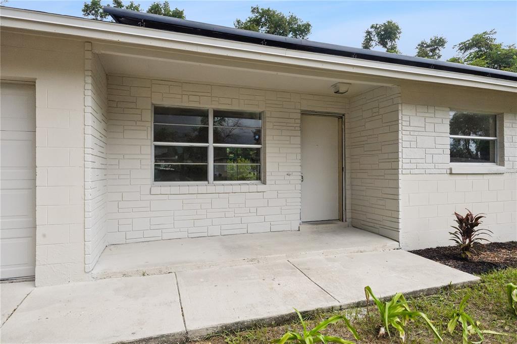 The exterior of a house features a concrete porch, a white door, and light-colored masonry — 3688 RUNDO DRIVE, ORLANDO, FL